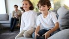 Two kids sitting on sofa with playing video games