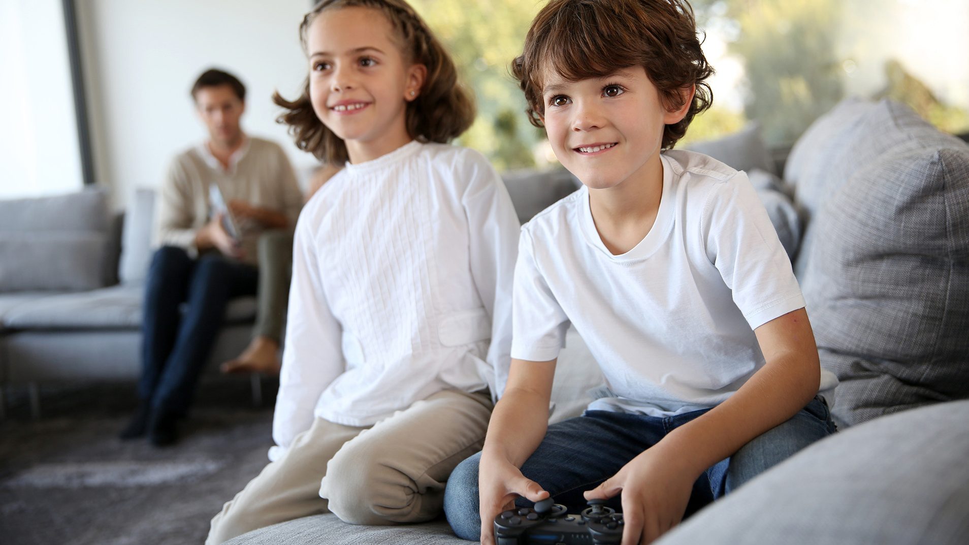 Two kids sitting on sofa with playing video games