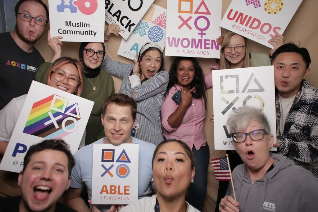 Group photo of Sony Interactive employees holding signs of employee network logos